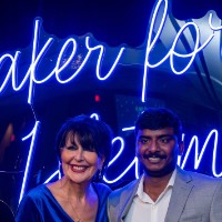 Boy in gray suit with President Mantella in front of neon sign